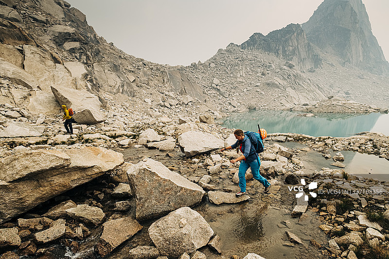 女徒步者穿越布加布山脉的高山溪流图片素材