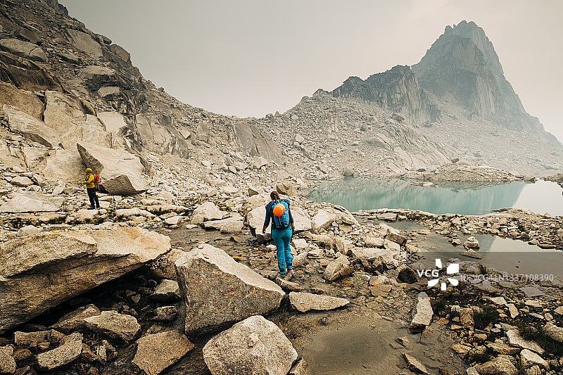 女徒步者穿越布加布山脉的高山溪流图片素材
