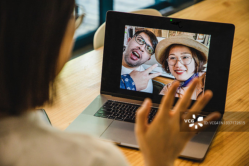 亚洲女人用笔记本电脑给度假中的情侣朋友打视频电话图片素材