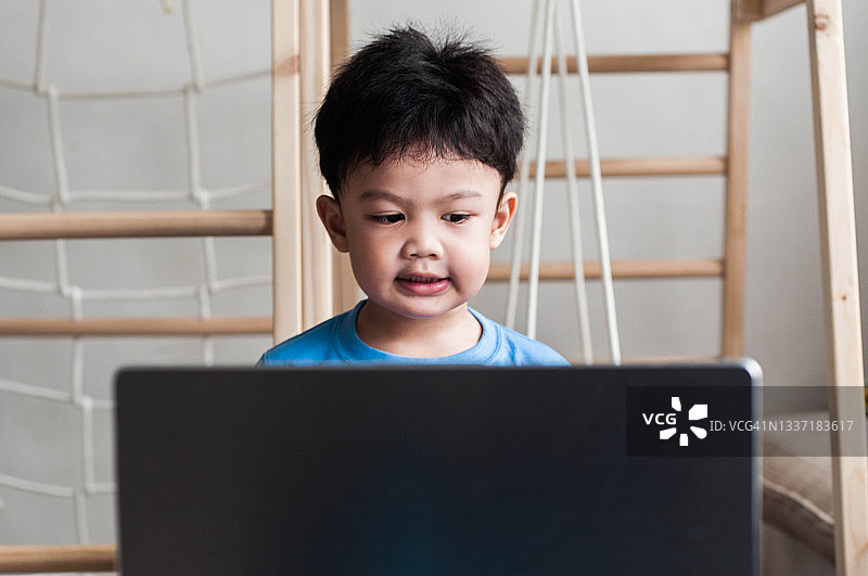 一位东南亚男童在家中使用笔记本电脑上网课图片素材