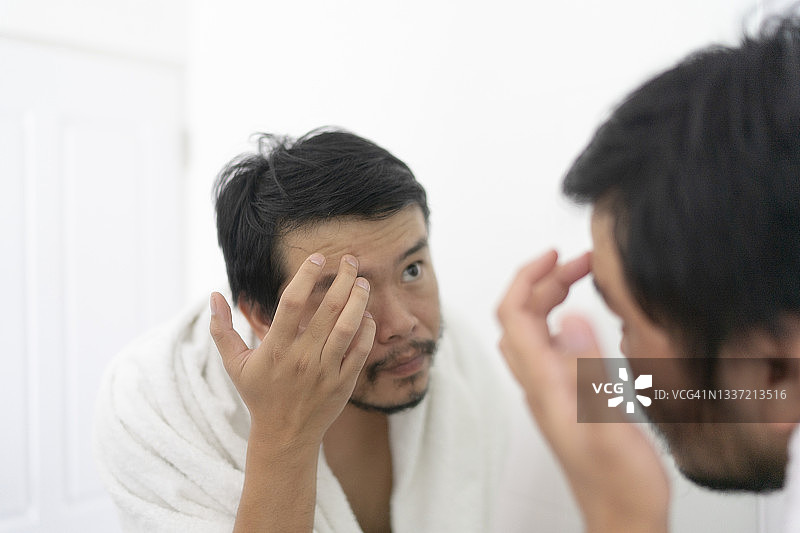 关注面部肌肤护理的亚洲青年图片素材