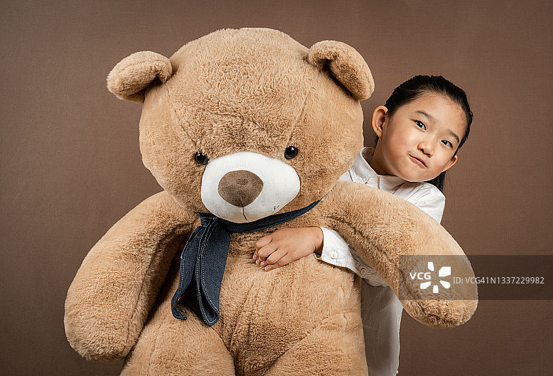 棕色背景下拥抱泰迪熊的女孩图片素材