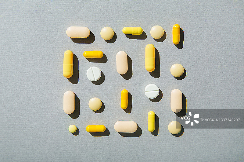 灰色背景上的黄色药丸和胶囊：极简医疗概念，平铺，俯视图片素材