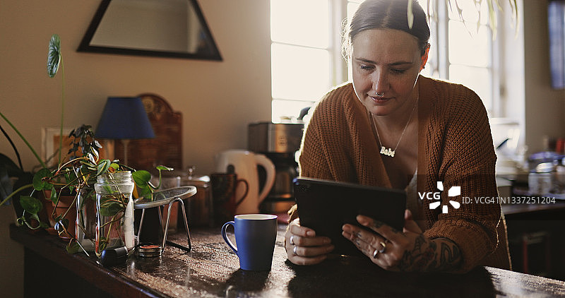 年轻女人在家用平板电脑喝咖啡图片素材