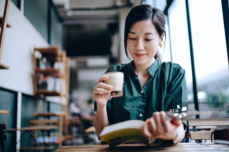 年轻亚洲女性在咖啡馆休息，享受咖啡和阅读时光图片素材