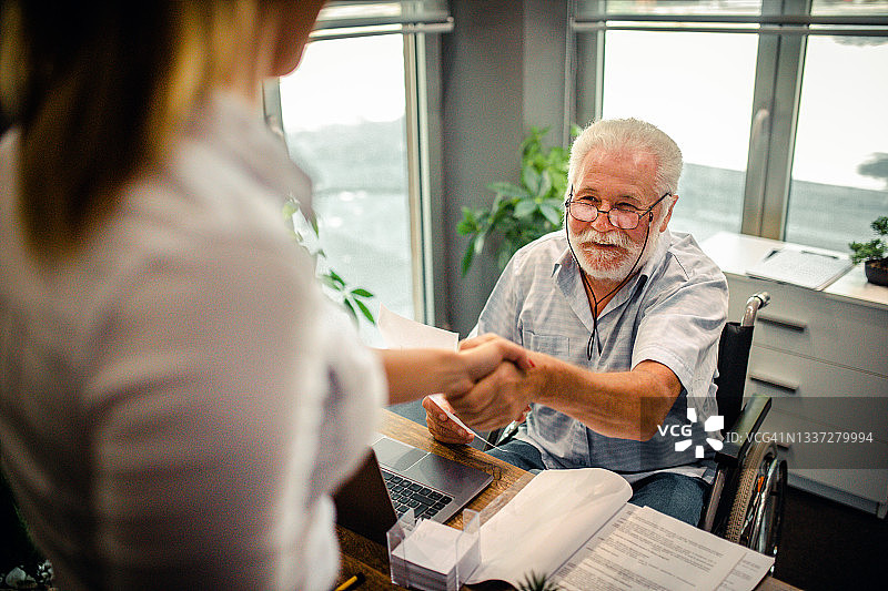 坐在轮椅上的残疾老人在办公室里图片素材