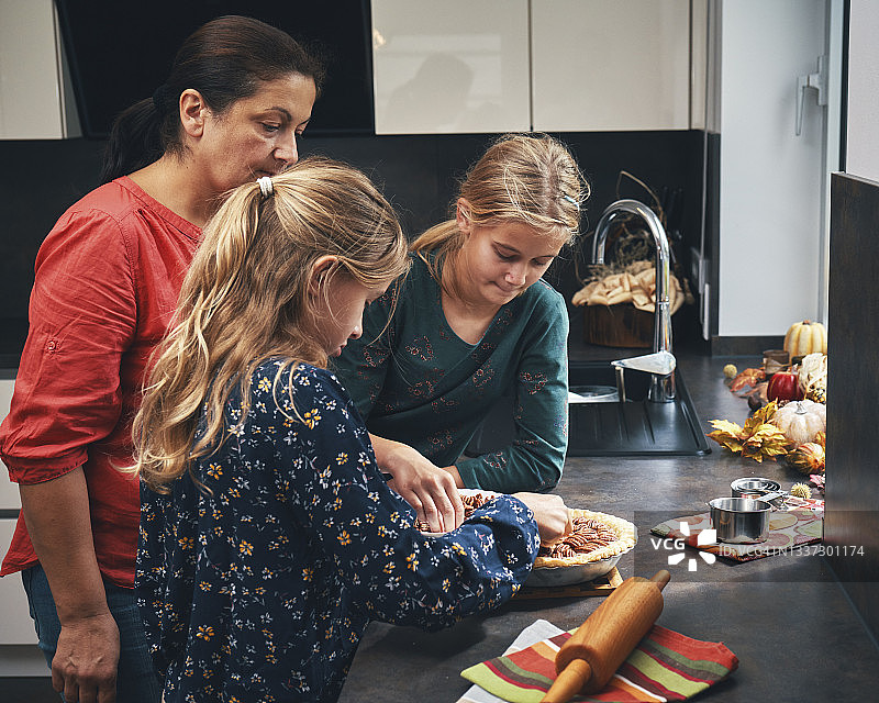 母亲和青少年准备节日山核桃派图片素材