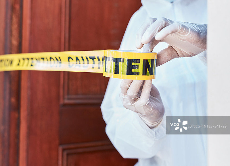 一位身穿防护服的工作人员用警戒带隔离区域的特写镜头图片素材