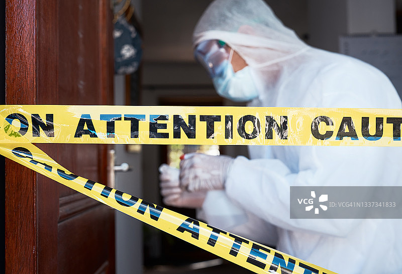 门口的警戒线特写，背景是穿着防护服的工人图片素材