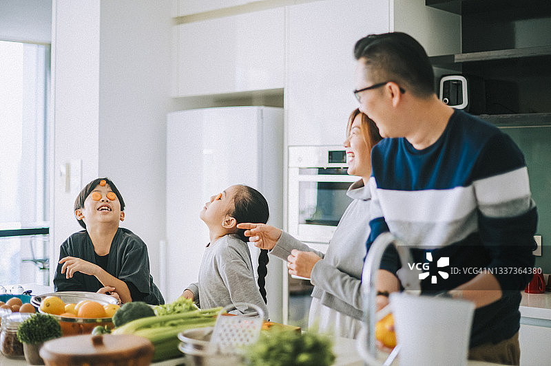 快乐的华裔年轻家庭与2个孩子在厨房准备食物，享受欢乐时光图片素材