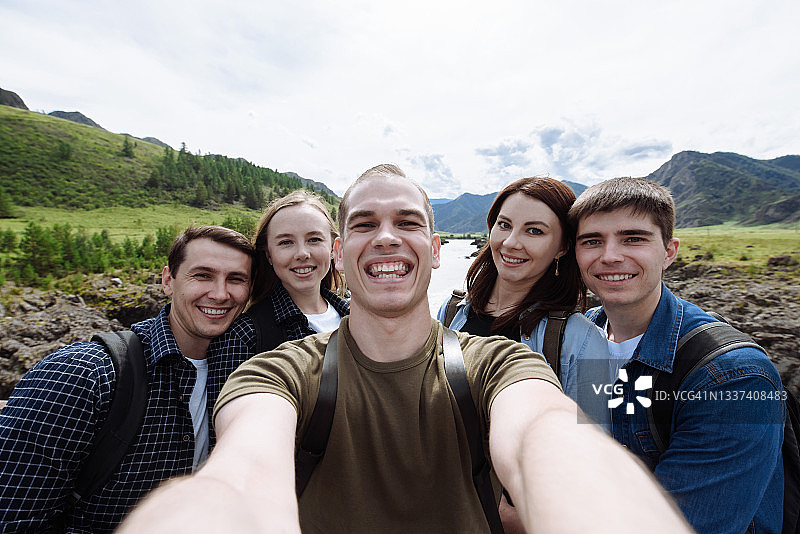 一群快乐微笑的朋友在山间溪流的背景下自拍图片素材