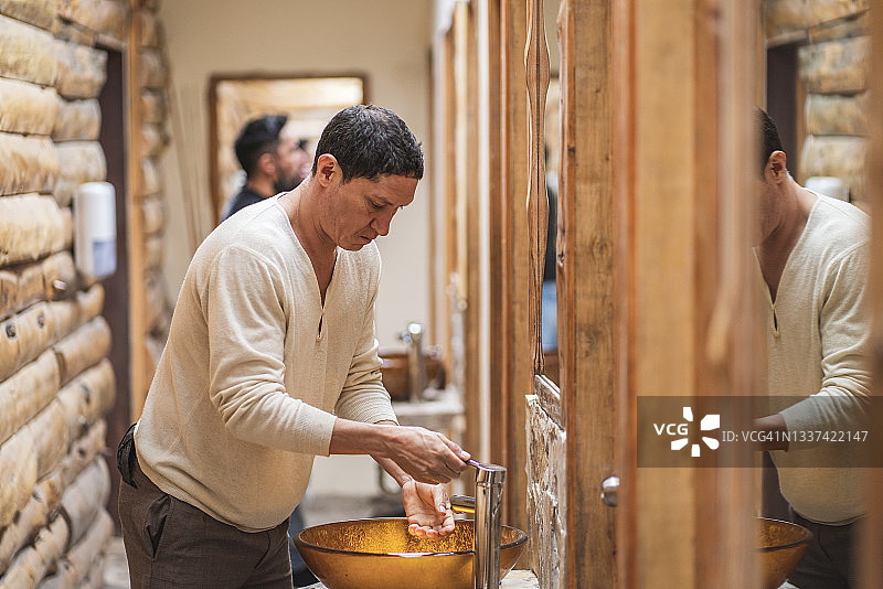 拉丁裔男子抵达乡间别墅并在那里度假，他正在洗手图片素材