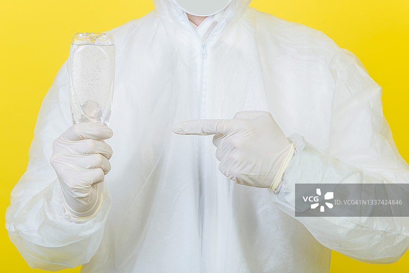 用洗手液保护双手免受新冠病毒侵害。穿防护服（PPE）的男人展示手指特写。图片素材