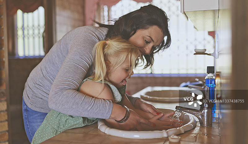 年轻母亲帮助女儿洗手图片素材