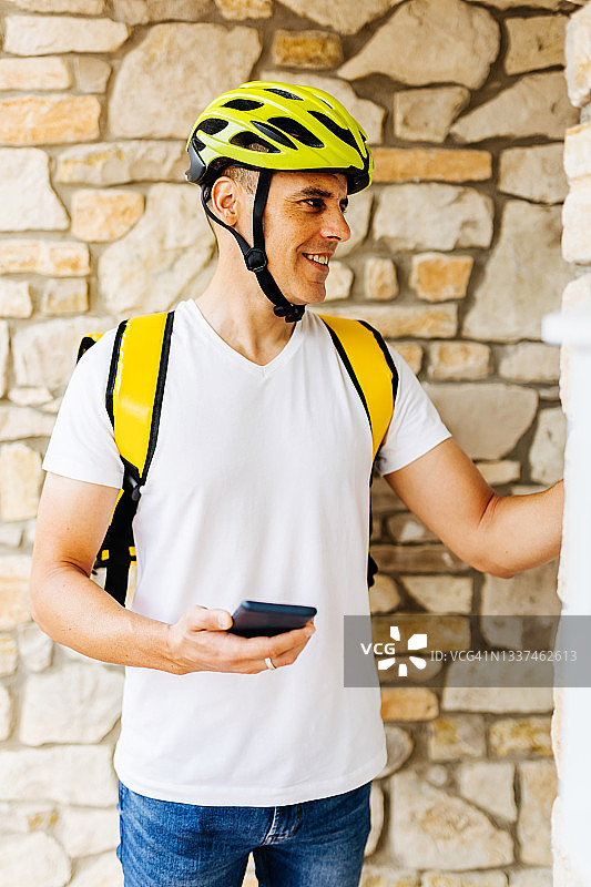 微笑的送货员用手机按公寓的门铃图片素材