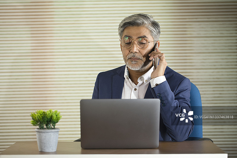 商人用手机处理笔记本电脑工作图片素材