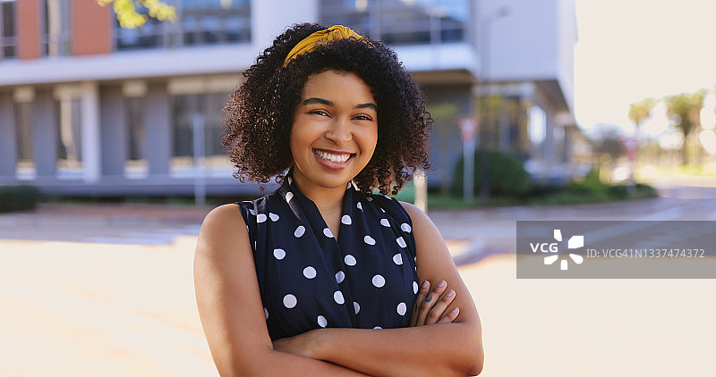 一位自信的年轻女商人站在城市里，双臂交叉的肖像图片素材
