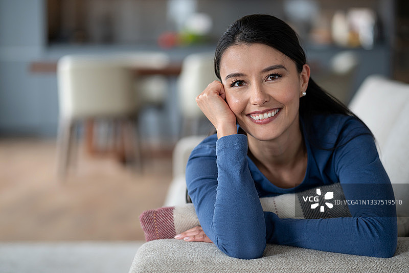 在家放松地躺在沙发上微笑的快乐女人图片素材