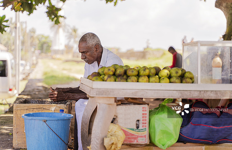 斯里兰卡加勒街头，正在清洁削芒果的老年男性小贩图片素材