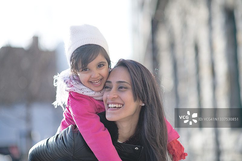 穆斯林母亲给小女儿背背图片素材