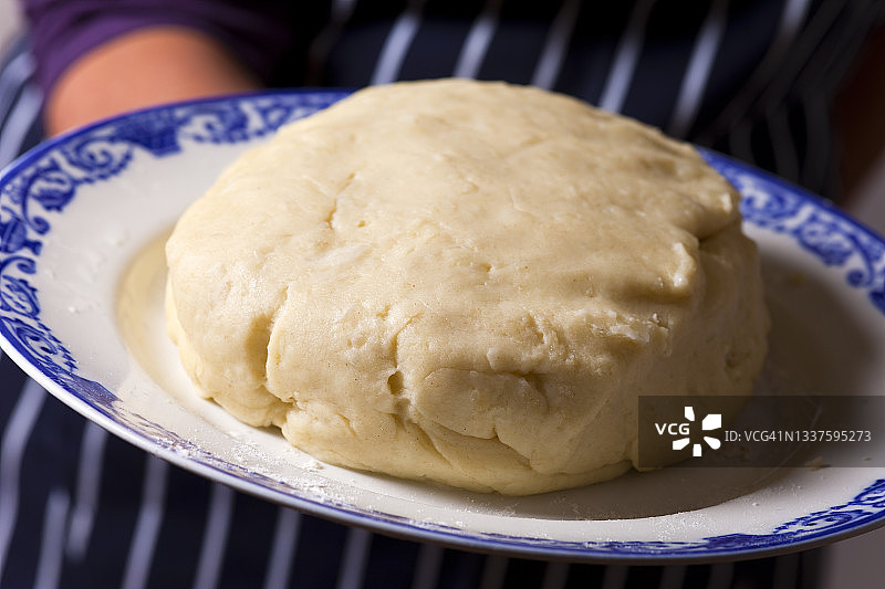 放在复古蓝白盘子里的大司康面团图片素材