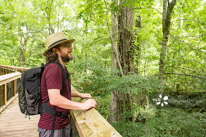 男子站在佛罗里达州伊切图克尼泉州立公园森林的木板路上图片素材