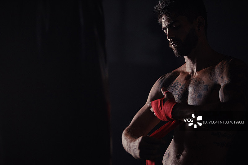 英俊的年轻男子独自站在健身房，戴着拳击护腕图片素材