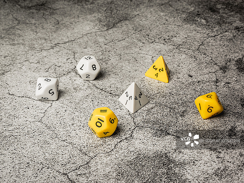水泥背景上的白色和黄色角色扮演骰子图片素材