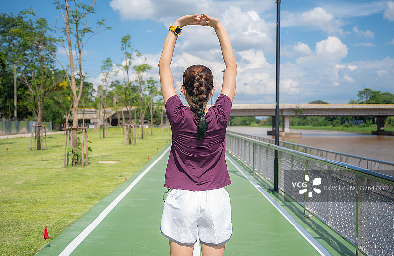 女子在公园跑步前伸展和热身的后视图图片素材