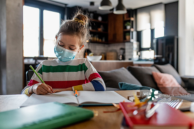 女学生戴着口罩在家做作业图片素材