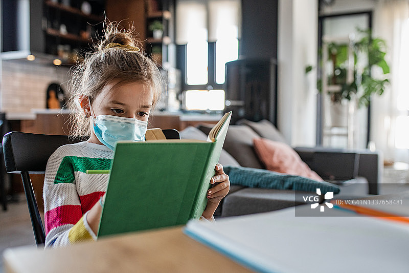 女学生戴着口罩在家做作业图片素材