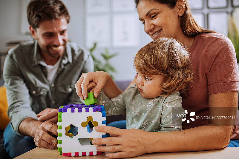 在家中，和两个女儿一起玩玩具的全家福。母亲怀孕了图片素材