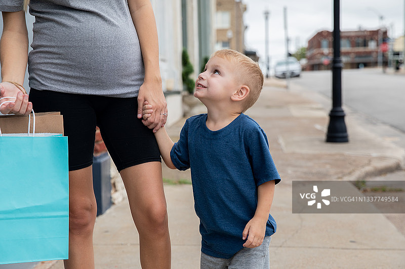 儿子购物时抬头看母亲并微笑图片素材