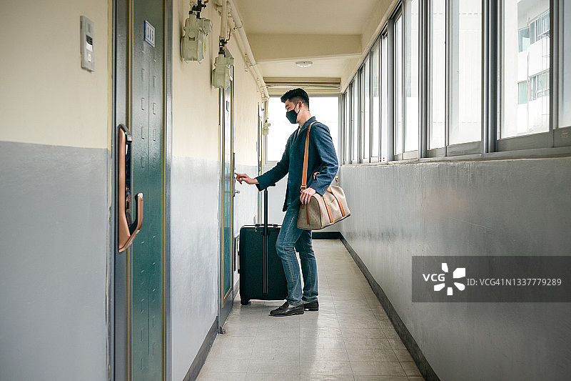 年轻男人携带行李箱开门的侧视图图片素材