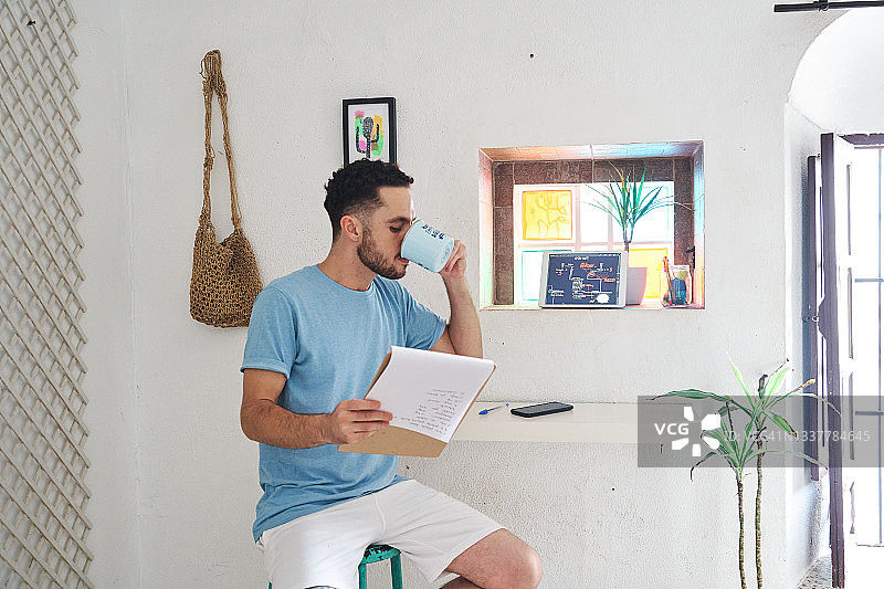 男人喝咖啡看笔记居家办公图片素材