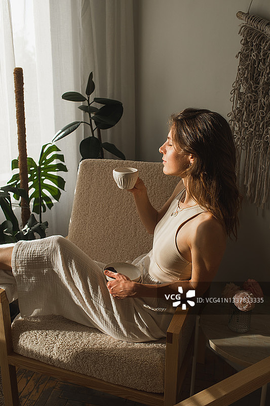 在舒适阳光的公寓里喝早咖啡的美丽女人图片素材
