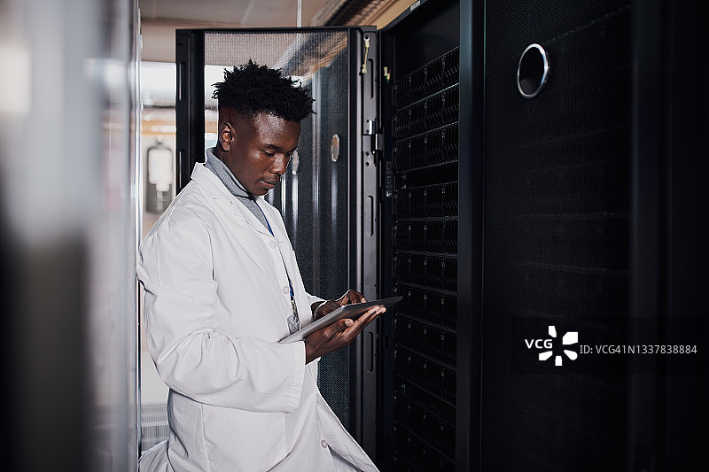 年轻男人在工作场所的服务器机房中使用平板电脑的镜头图片素材
