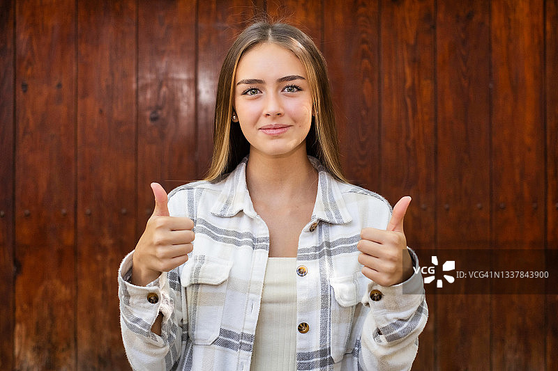竖起大拇指，看着镜头的年轻拉丁裔女子图片素材