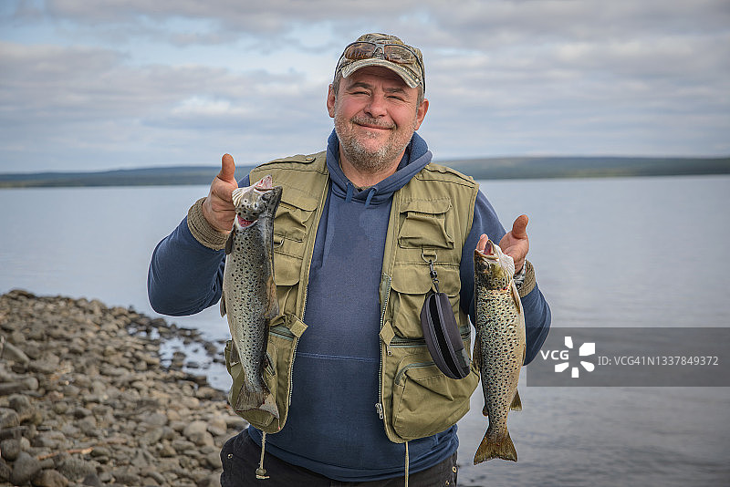 一名男子捕获了一条鳟鱼图片素材