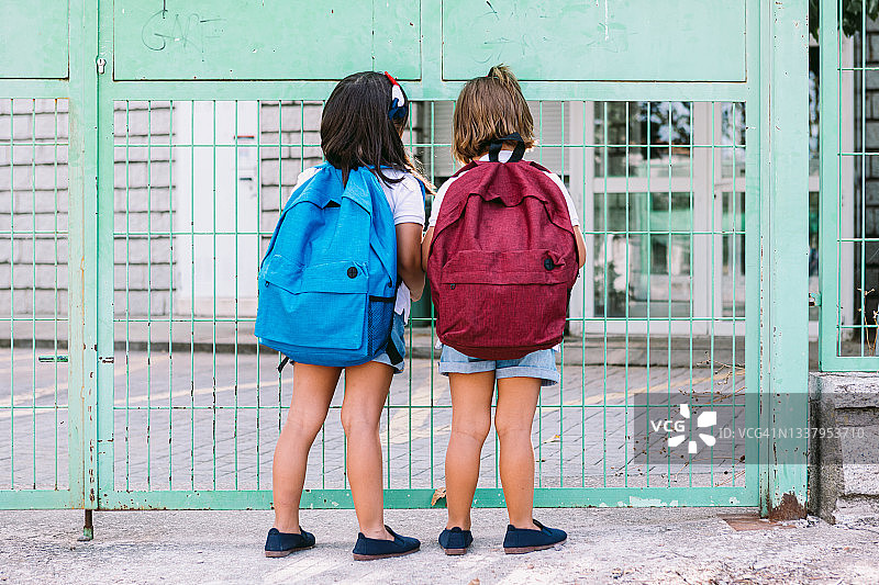 开学日，背着书包在学校绿门前的女孩图片素材