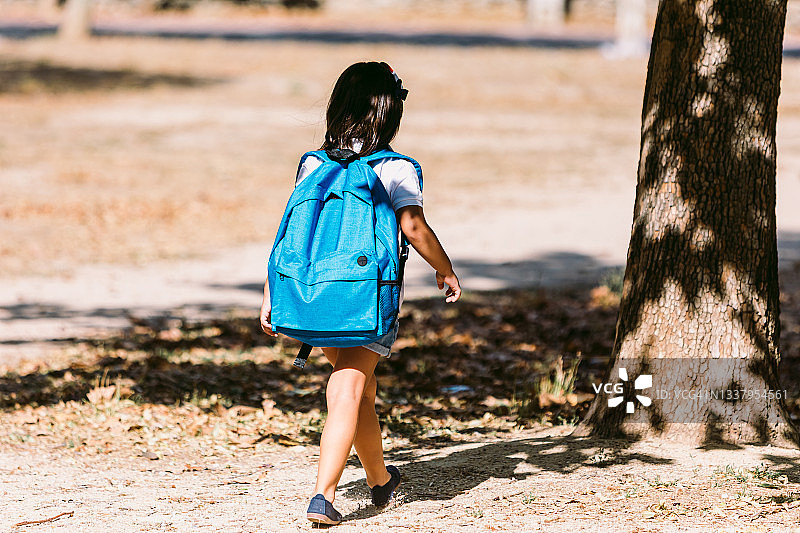 背着蓝色背包的黑发女孩走向学校图片素材