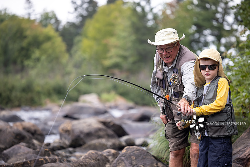 在魁北克河中钓鱼的可爱红发男孩和祖父图片素材