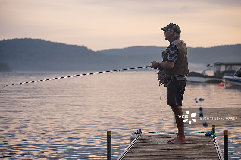 年长的男人在日落时分飞蝇钓鱼图片素材