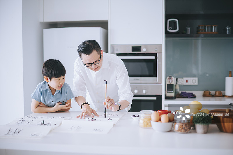 亚洲华人父亲教儿子练习中国书法图片素材