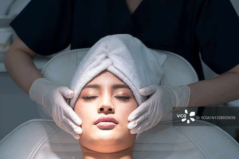 美容师在美容院为年轻女性做放松焕颜面部按摩，模特与医生图片素材