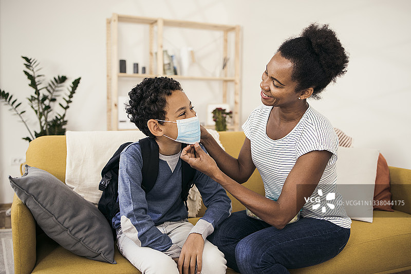 母亲帮儿子戴口罩准备上学图片素材