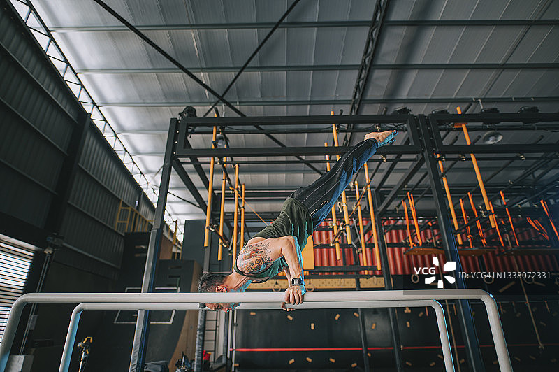 侧面视角：中国亚洲健壮男性运动员在健身房练习体操图片素材