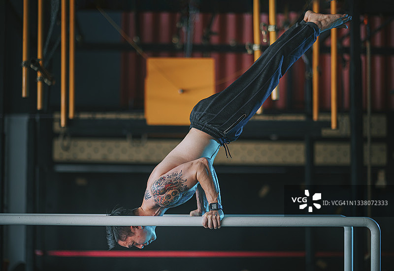侧面视角：中国亚洲健壮男性运动员在健身房练习体操图片素材