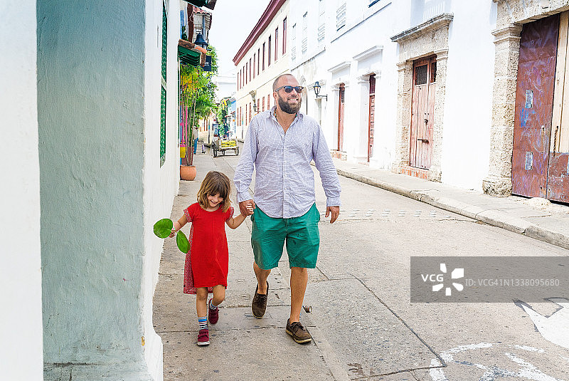 男人和孩子走在南美洲卡塔赫纳老殖民城市的街道上图片素材