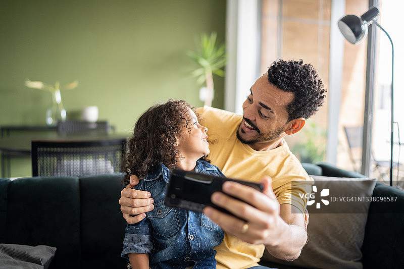 父子在家用智能手机观看或进行视频通话图片素材